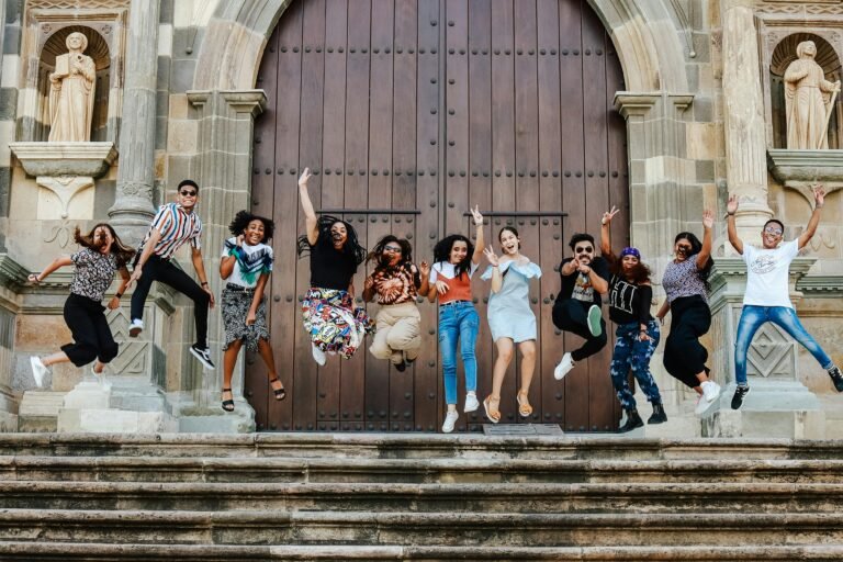 A lively group of friends joyfully jumping on steps outside a historic cathedral.