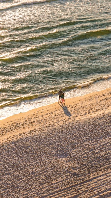 pexels-photo-19630742-19630742 A couple enjoying a romantic walk on a sandy beach with waves in the background.